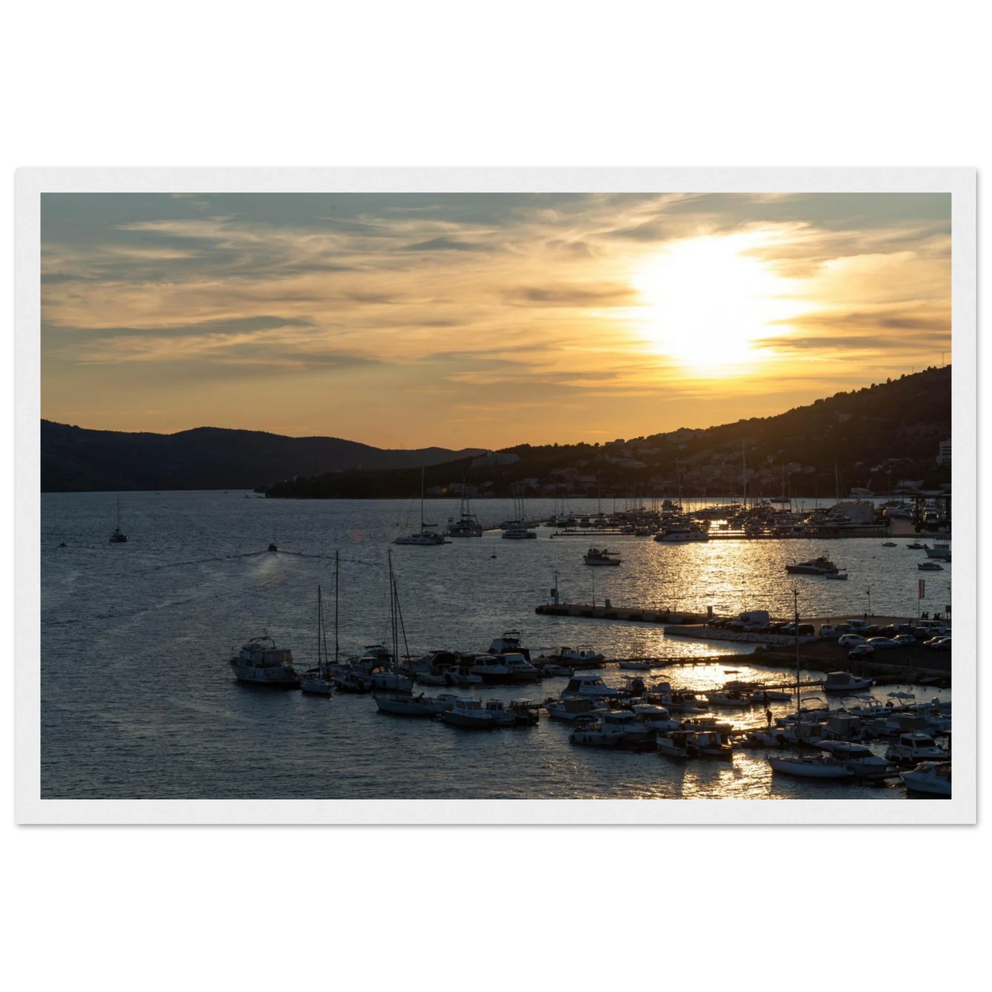 Wooden framed wall art of small boats anchored in a seaside port during Sunset at the harbor