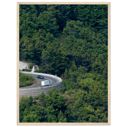 Aerial view of a winding road curve with cars surrounded by lush green forest landscape on wooden framed wall art