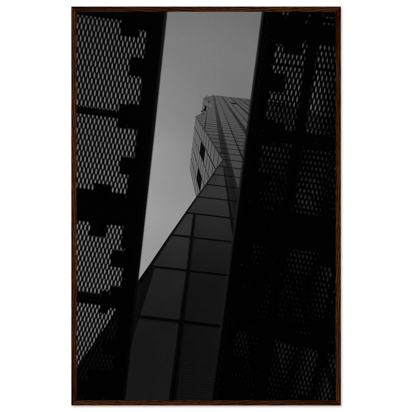 Black and white Low angle view looking up at a tall glass skyscraper framed between two metal structural elements on Wooden frame wall art