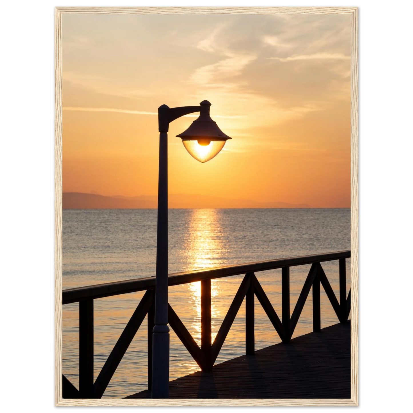 Wooden framed wall art of a sunset over the sea with a street lamp on the pier