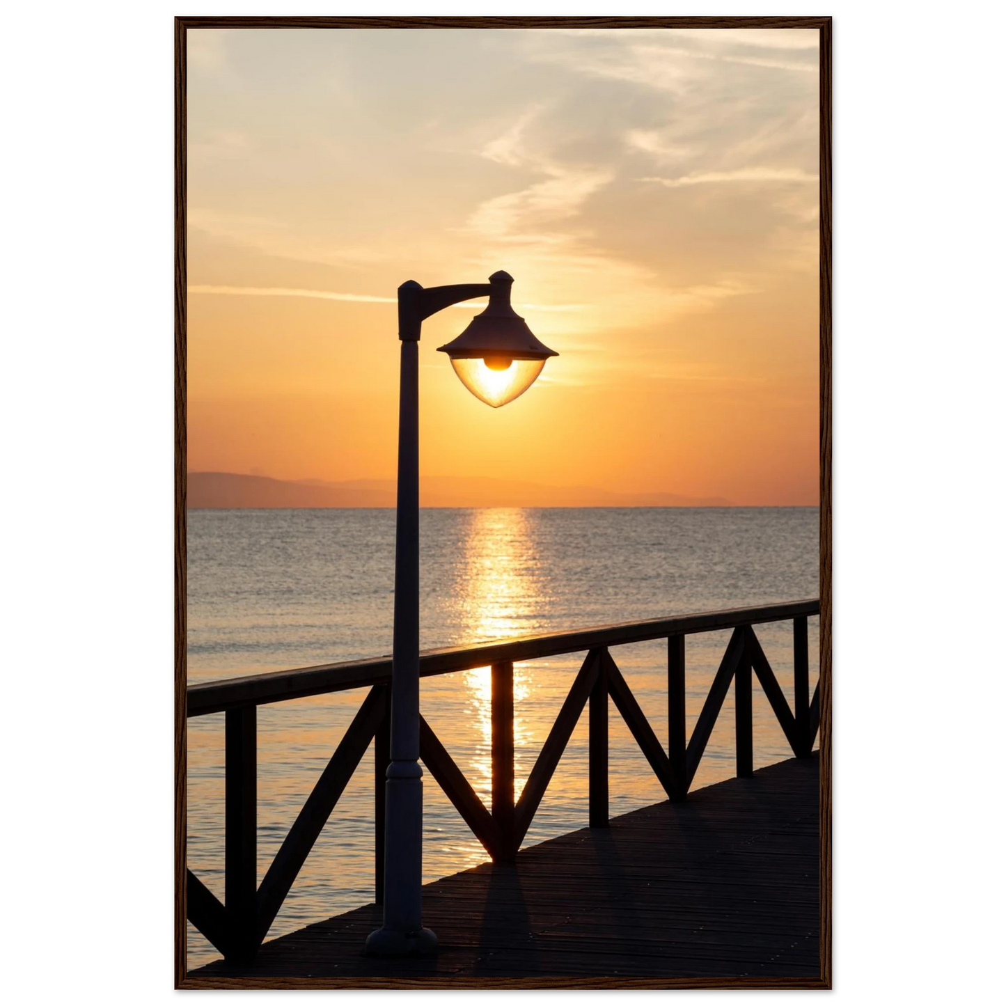 Wooden framed wall art of a sunset over the sea with a street lamp on the pier