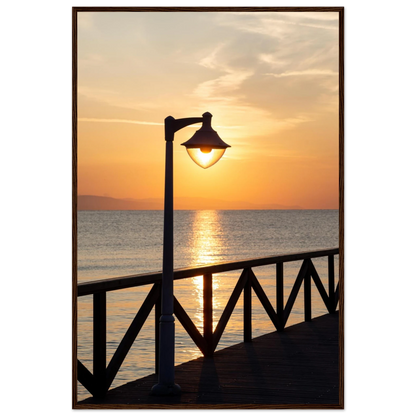 Wooden framed wall art of a sunset over the sea with a street lamp on the pier