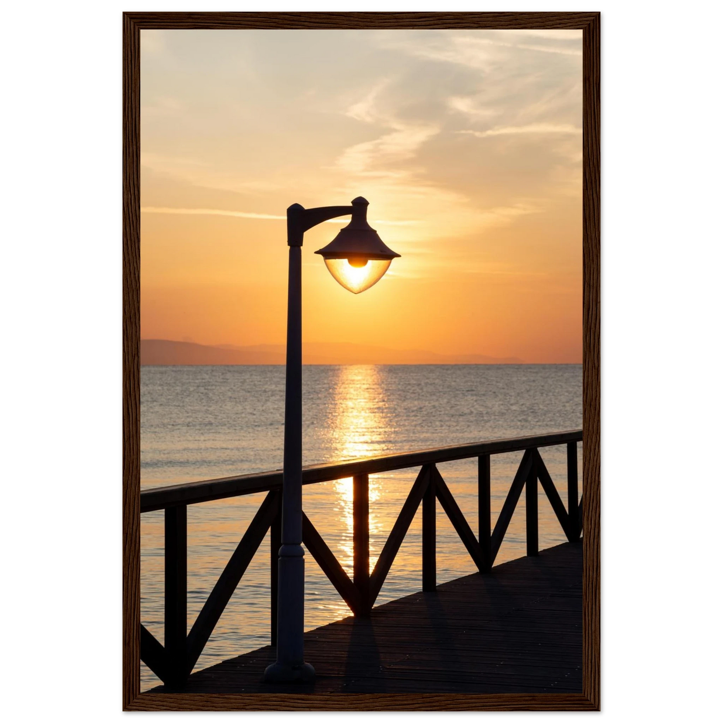Wooden framed wall art of a sunset over the sea with a street lamp on the pier