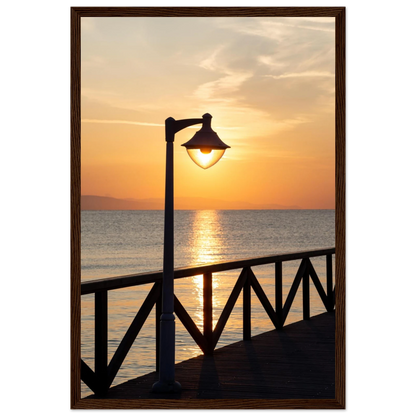 Wooden framed wall art of a sunset over the sea with a street lamp on the pier