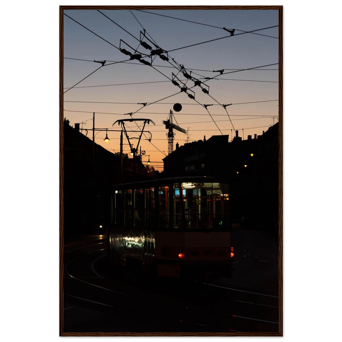Wooden framed wall art featuring a tram the Nightline driving between houses under power lines during a golden sunset