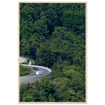 Aerial view of a winding road curve with cars surrounded by lush green forest landscape on wooden framed wall art