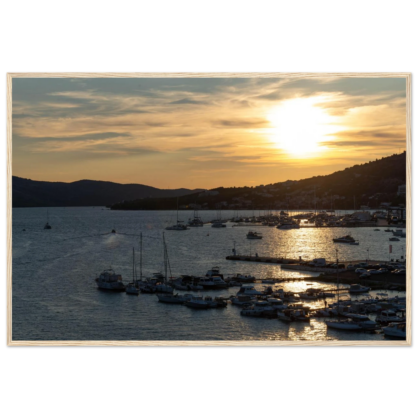 Wooden framed wall art of small boats anchored in a seaside port during Sunset at the harbor