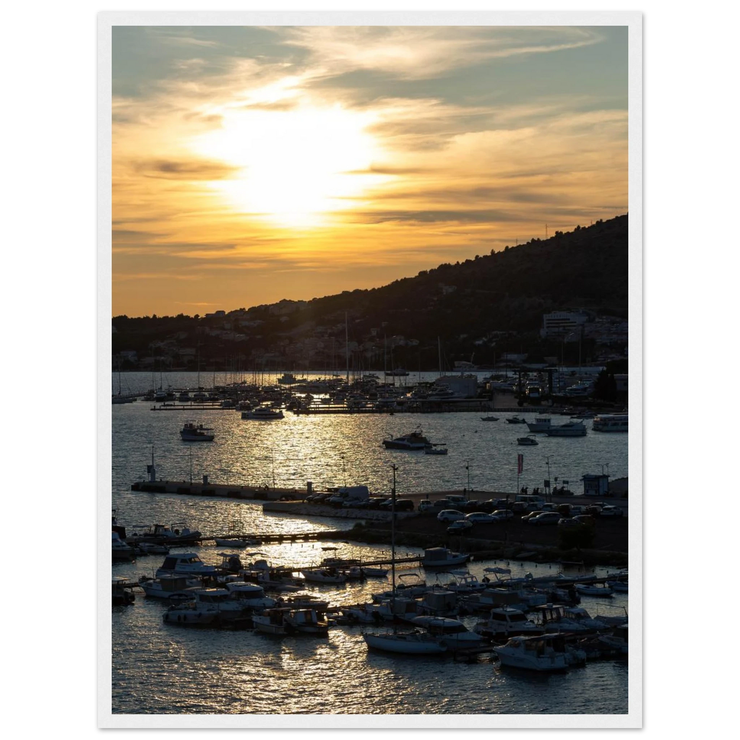 Wooden framed wall art of small boats anchored in a seaside port during Sunset at the harbor