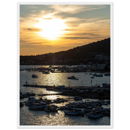 Wooden framed wall art of small boats anchored in a seaside port during Sunset at the harbor