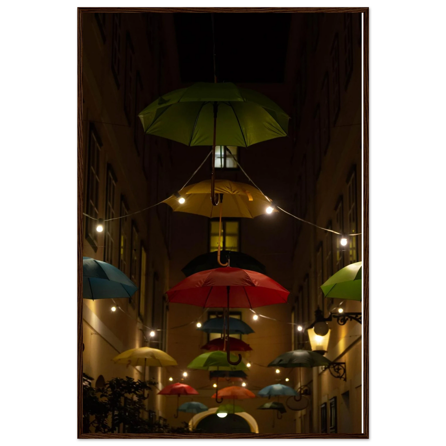 Nighttime street scene with colorful illuminated umbrellas hanging as decoration above a vibrant outdoor area on a wooden frame wall art