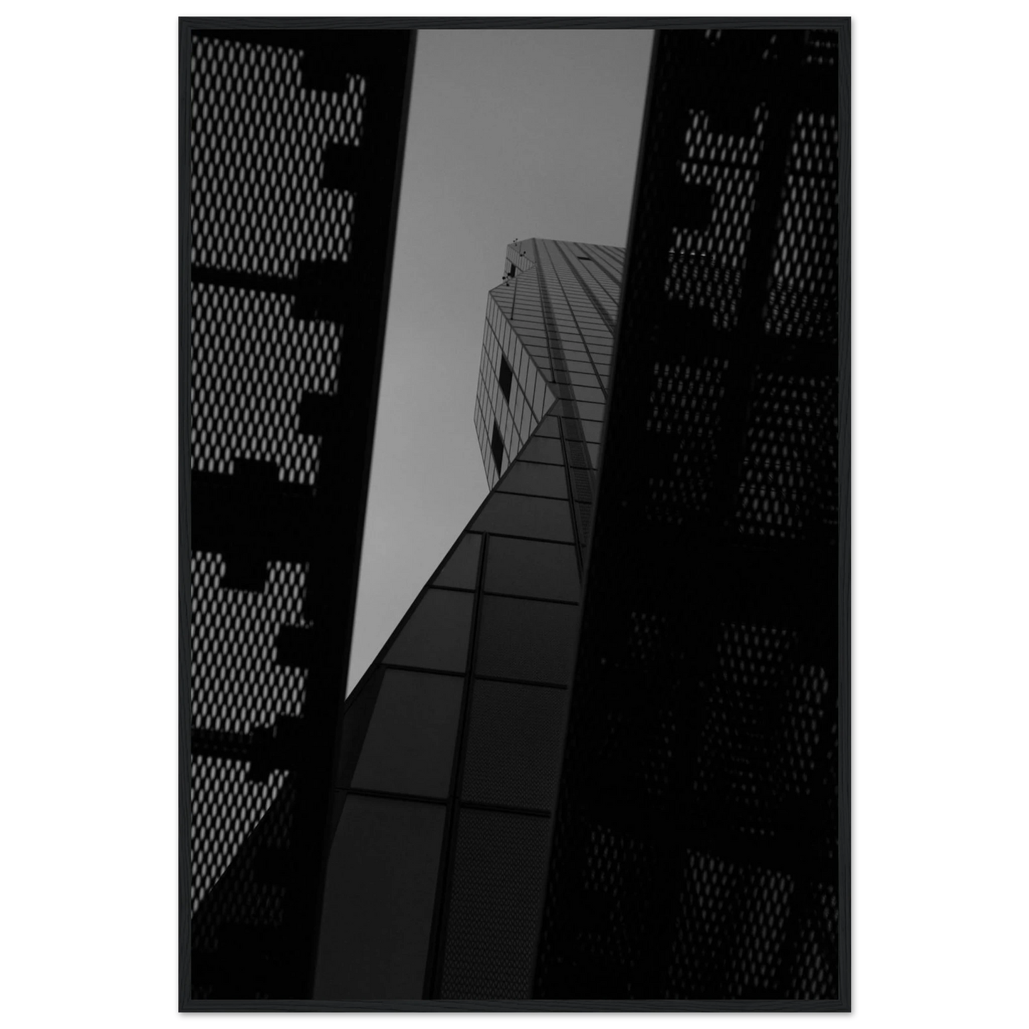 Black and white Low angle view looking up at a tall glass skyscraper framed between two metal structural elements on Wooden frame wall art