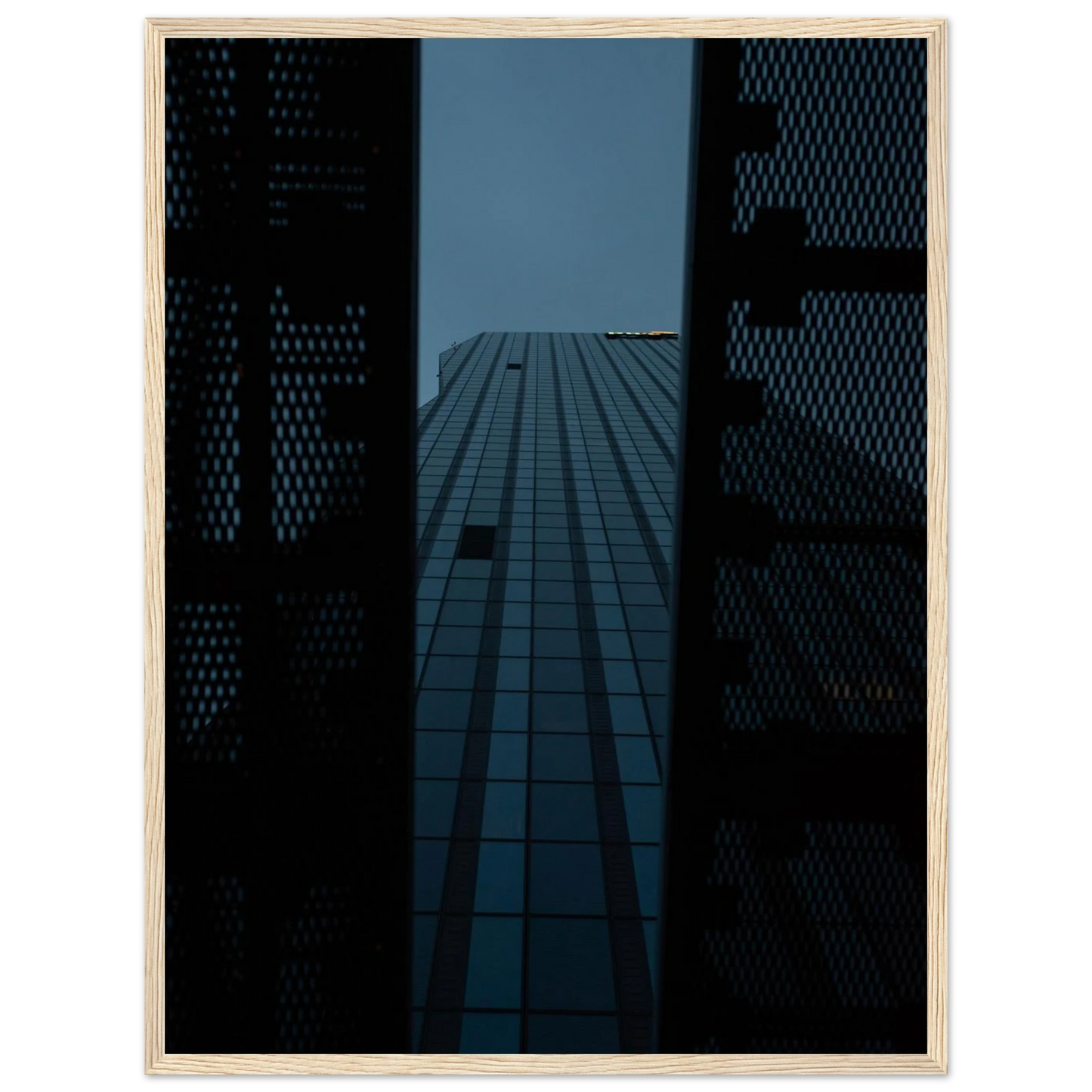 Low angle view looking up at a tall glass skyscraper framed between two metal structural elements on wooden framed wall art