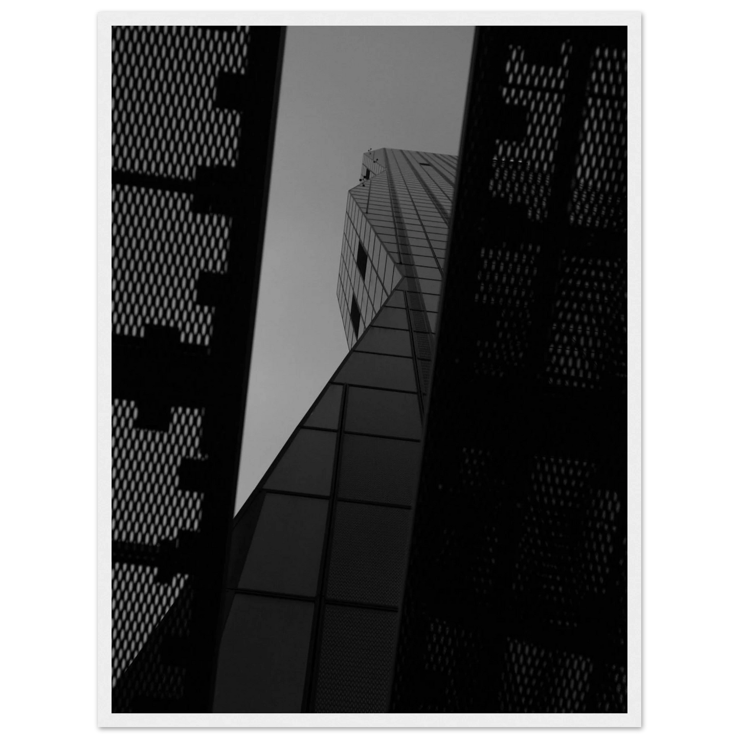 Black and white Low angle view looking up at a tall glass skyscraper framed between two metal structural elements on Wooden frame wall art