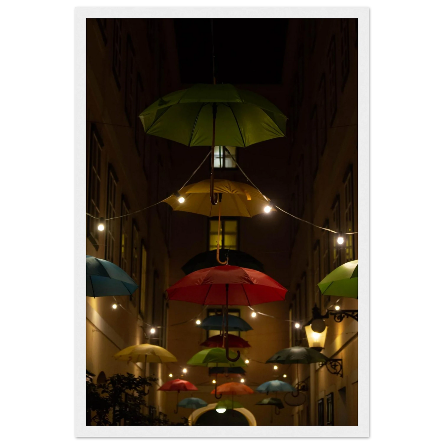Nighttime street scene with colorful illuminated umbrellas hanging as decoration above a vibrant outdoor area on a wooden frame wall art