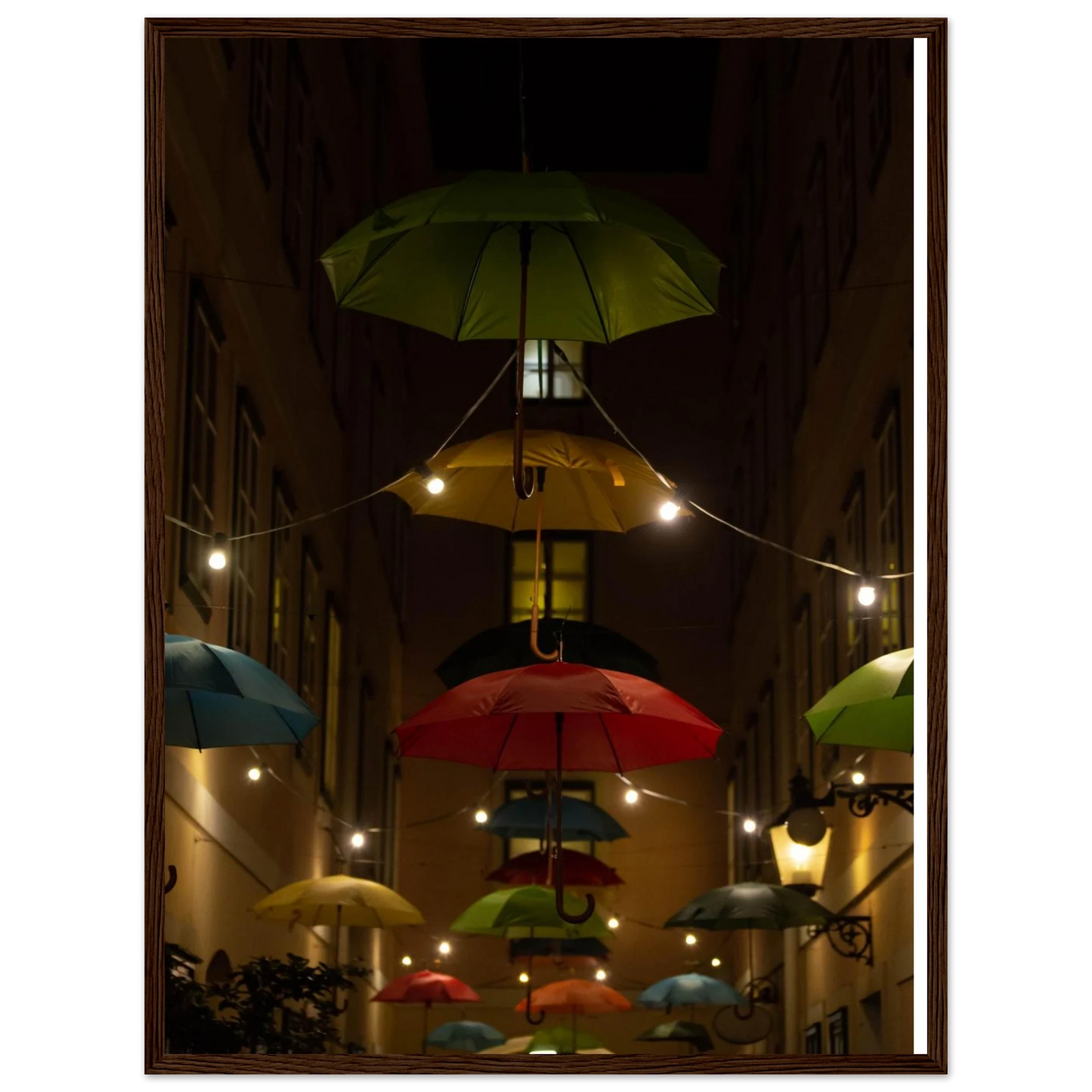 Nighttime street scene with colorful illuminated umbrellas hanging as decoration above a vibrant outdoor area on a wooden frame wall art