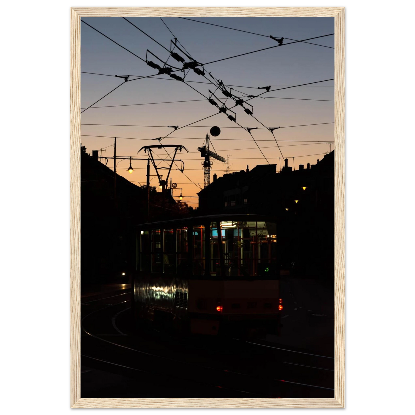 Wooden framed wall art featuring a tram the Nightline driving between houses under power lines during a golden sunset