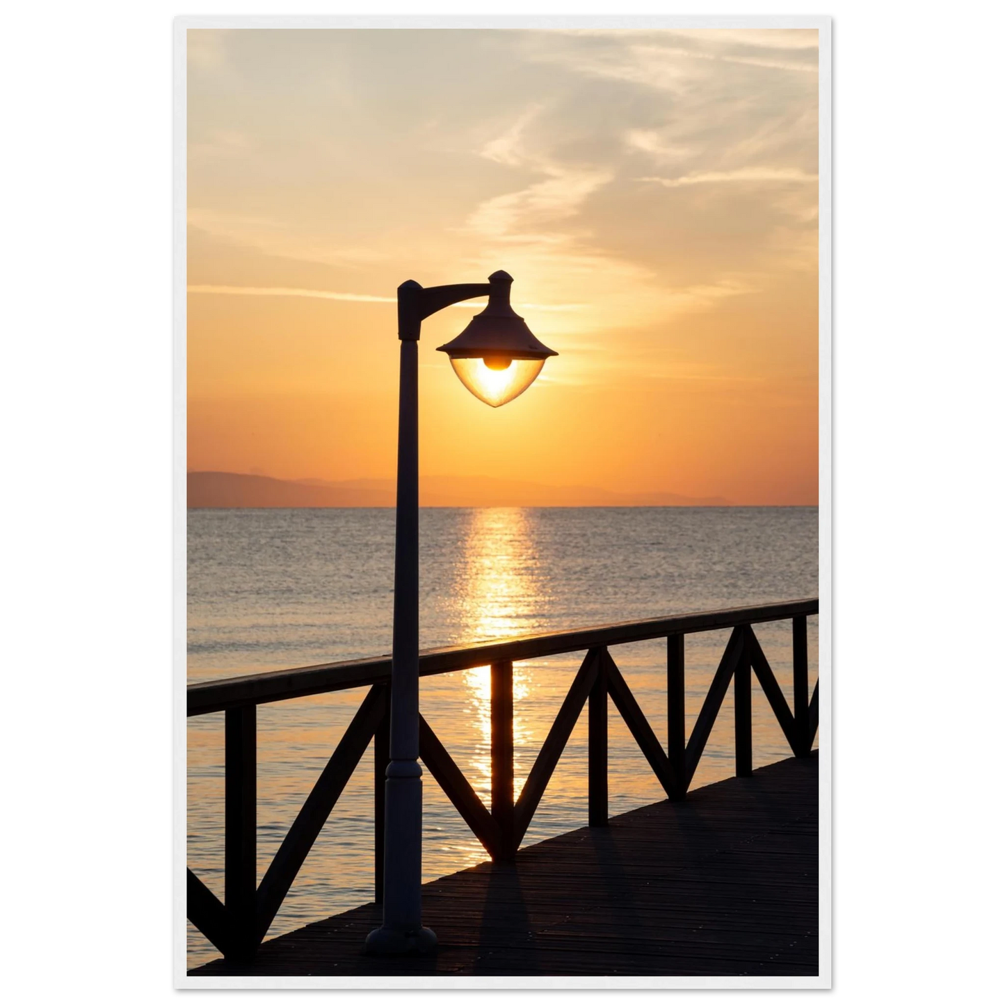 Wooden framed wall art of a sunset over the sea with a street lamp on the pier