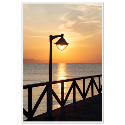 Wooden framed wall art of a sunset over the sea with a street lamp on the pier