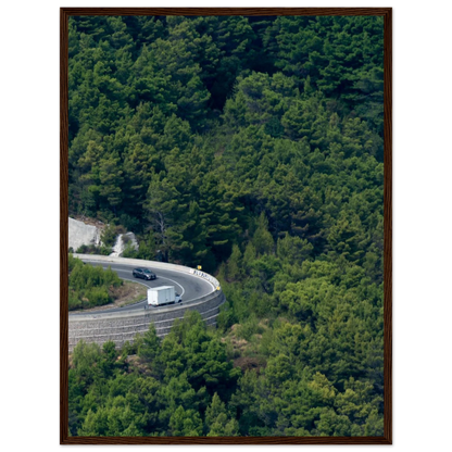 Aerial view of a winding road curve with cars surrounded by lush green forest landscape on wooden framed wall art