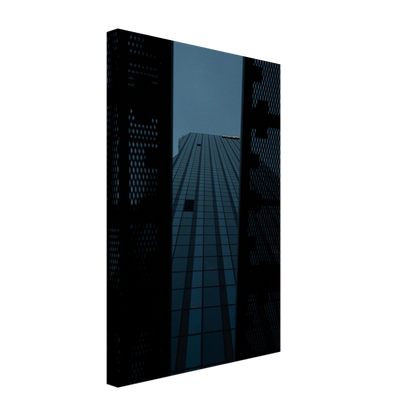 Low angle view looking up at a tall glass skyscraper framed between two metal structural elements on Canvas Print wall art