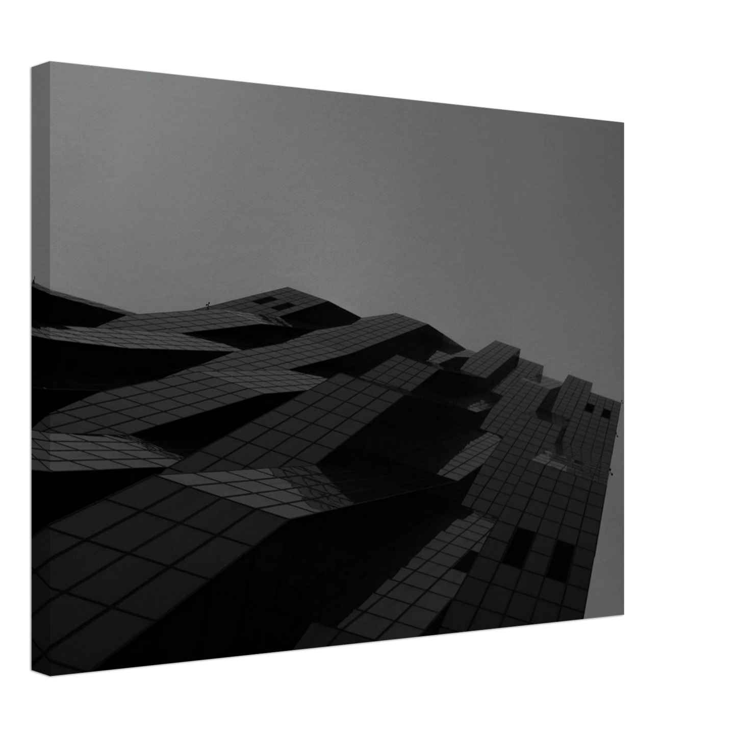 Black and white low angle view of a modern skyscraper with bold geometric lines and dark textured facade on Canvas Print wall art