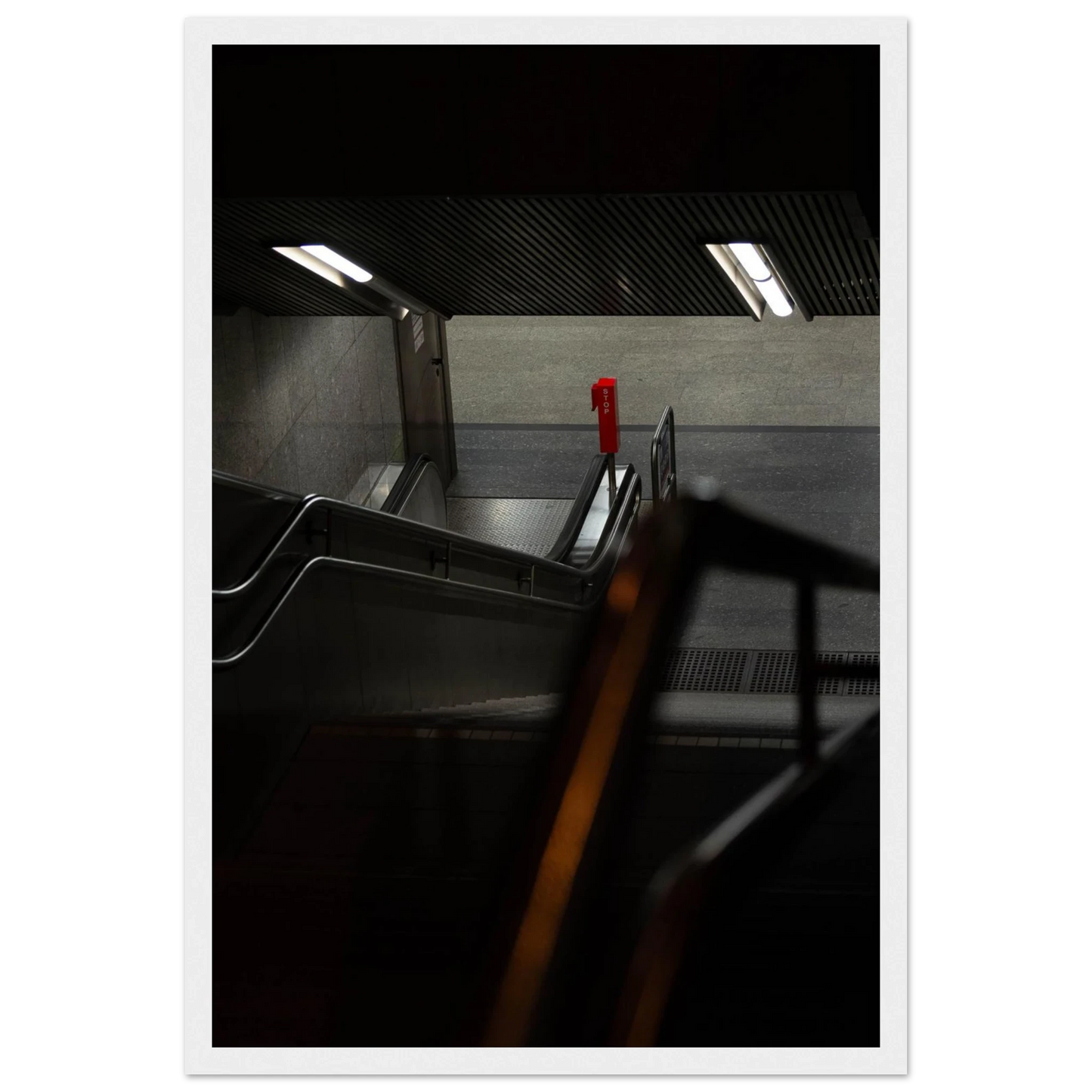 Nighttime view of a metro station entrance with illuminated signs and dark urban surroundings on wooden framed wall art