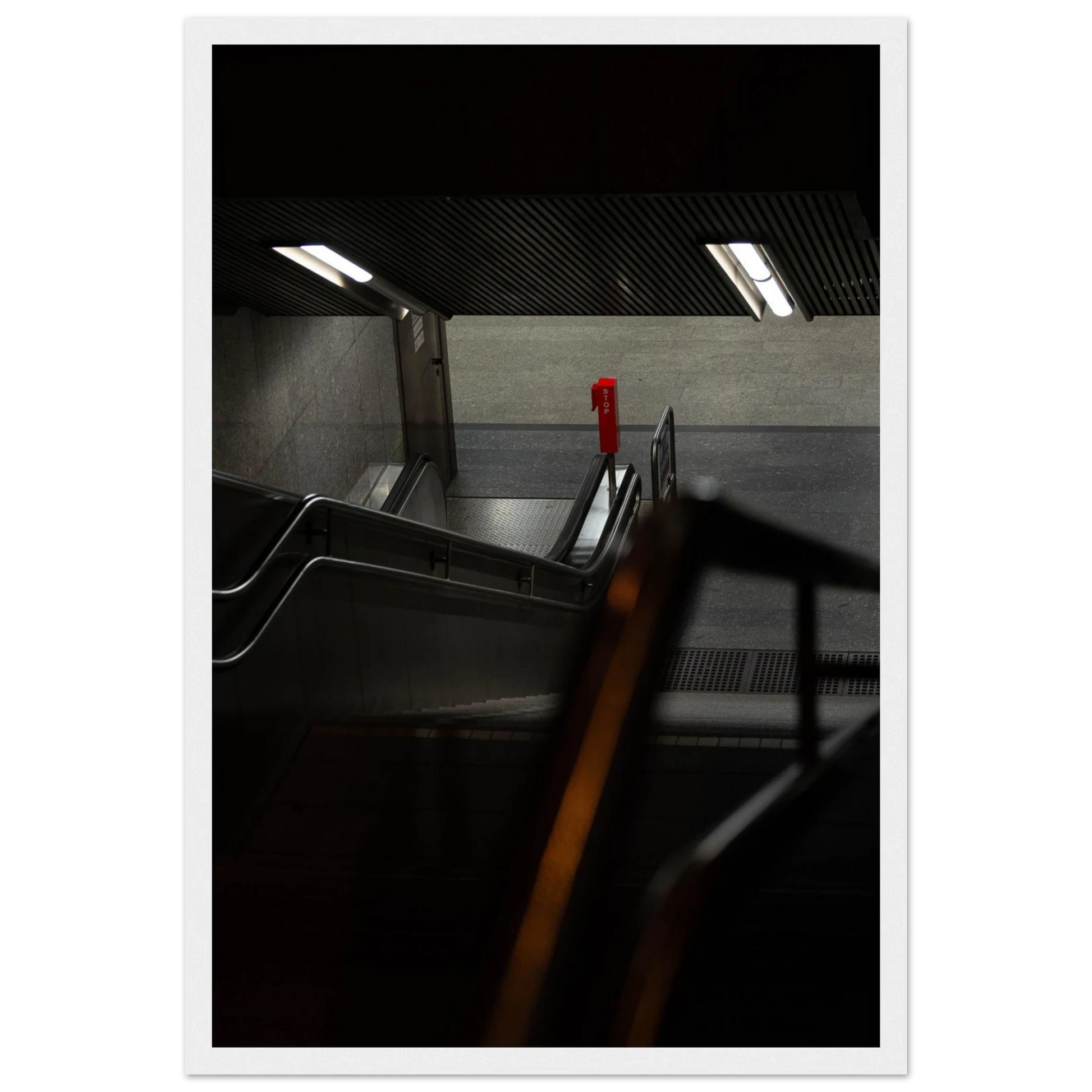 Nighttime view of a metro station entrance with illuminated signs and dark urban surroundings on wooden framed wall art