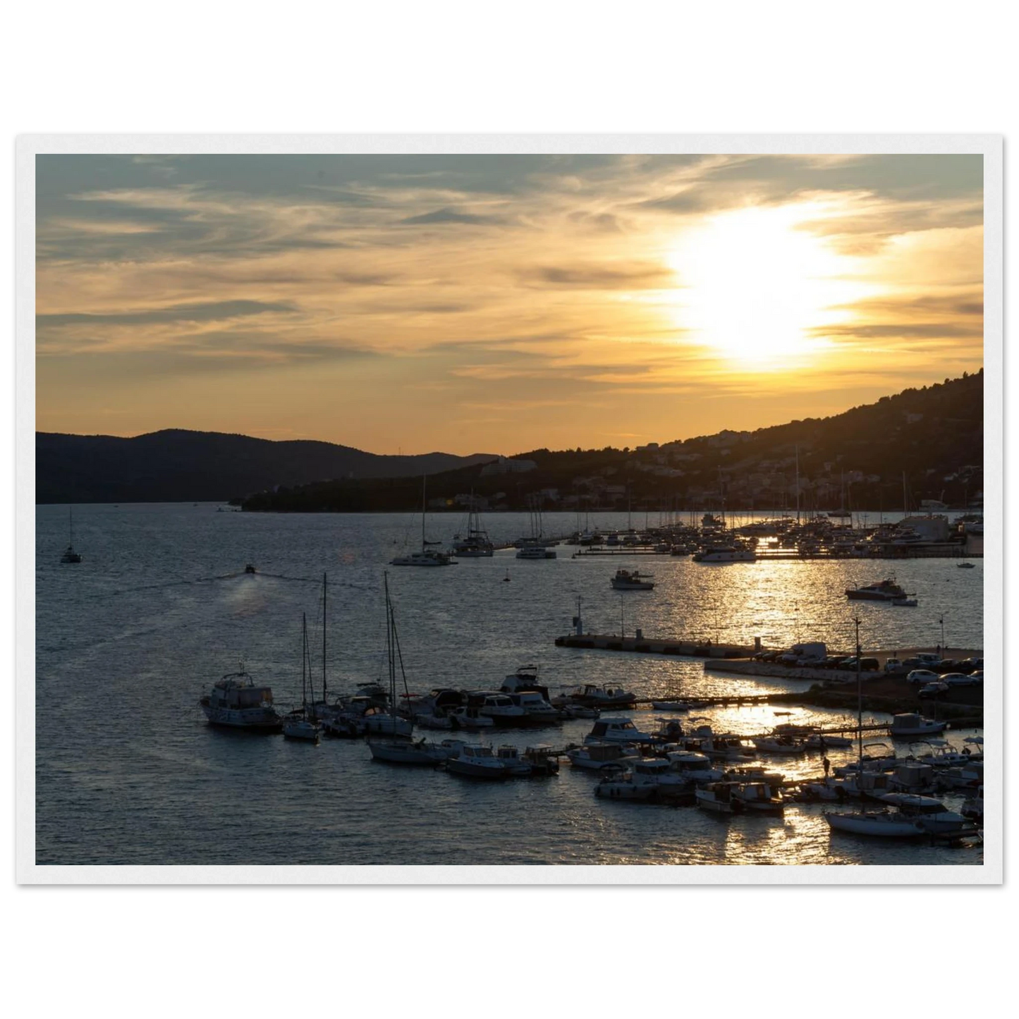 Wooden framed wall art of small boats anchored in a seaside port during Sunset at the harbor