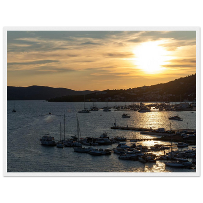 Wooden framed wall art of small boats anchored in a seaside port during Sunset at the harbor