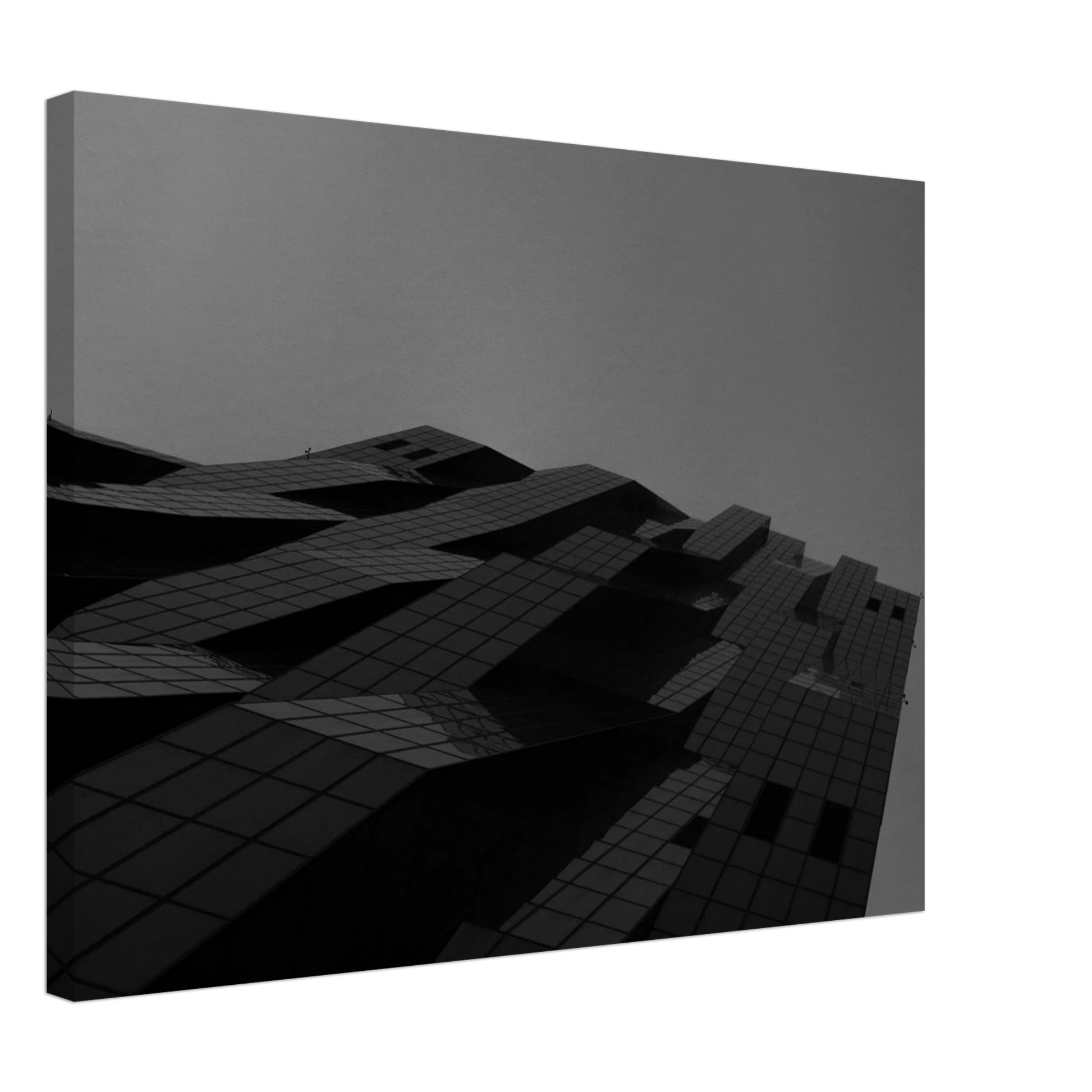 Black and white low angle view of a modern skyscraper with bold geometric lines and dark textured facade on Canvas Print wall art