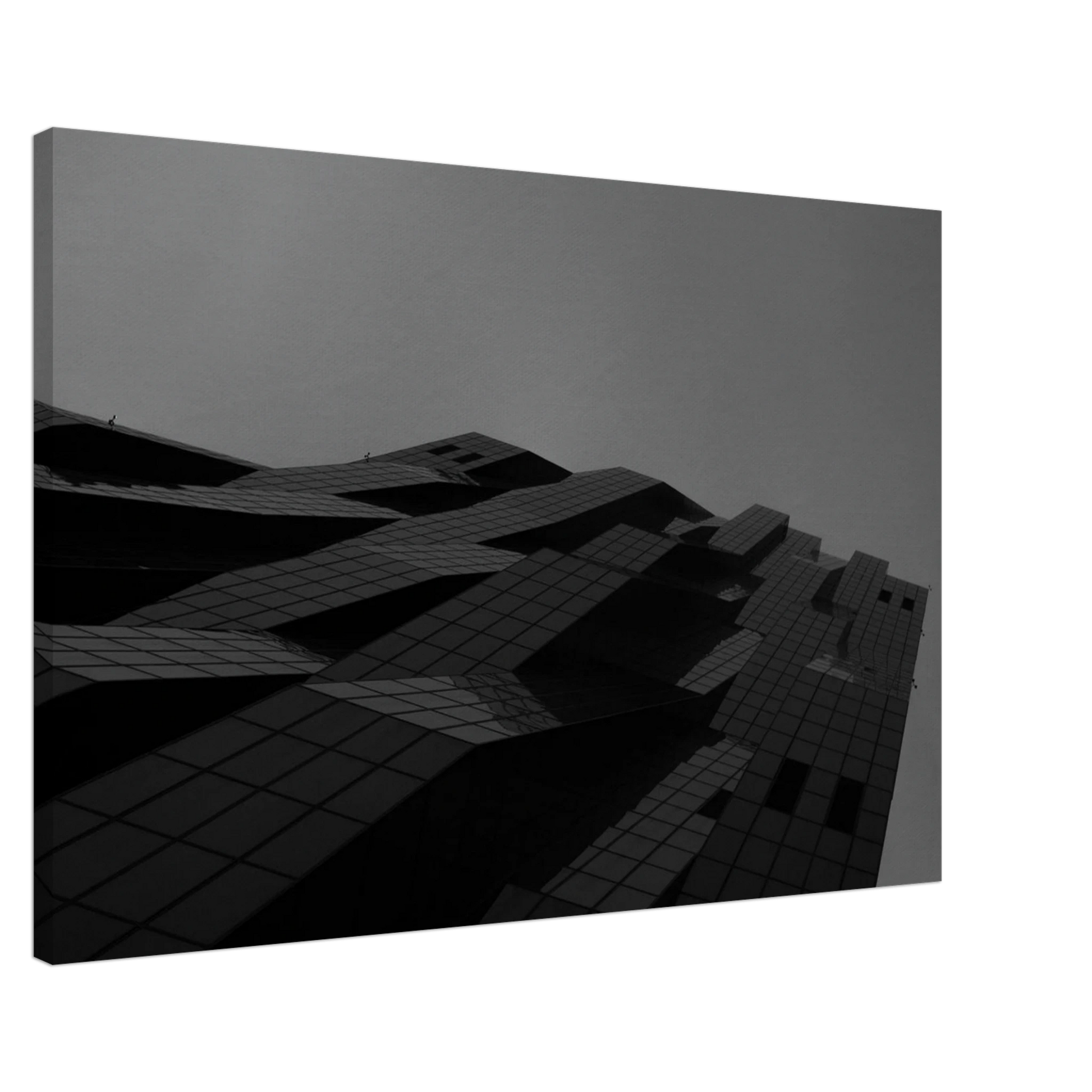 Black and white low angle view of a modern skyscraper with bold geometric lines and dark textured facade on Canvas Print wall art