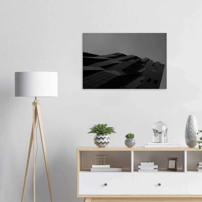 Black and white low angle view of a modern skyscraper with bold geometric lines and dark textured facade on Canvas Print wall art on the wall in the Livingroom