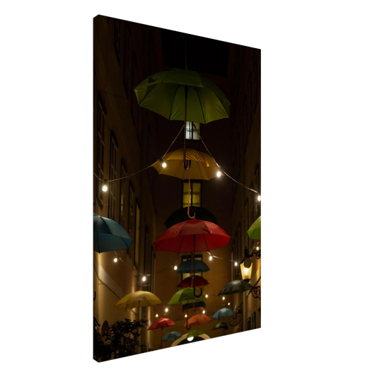 Nighttime street scene with colorful illuminated umbrellas hanging as decoration above a vibrant outdoor area on a Canvas print