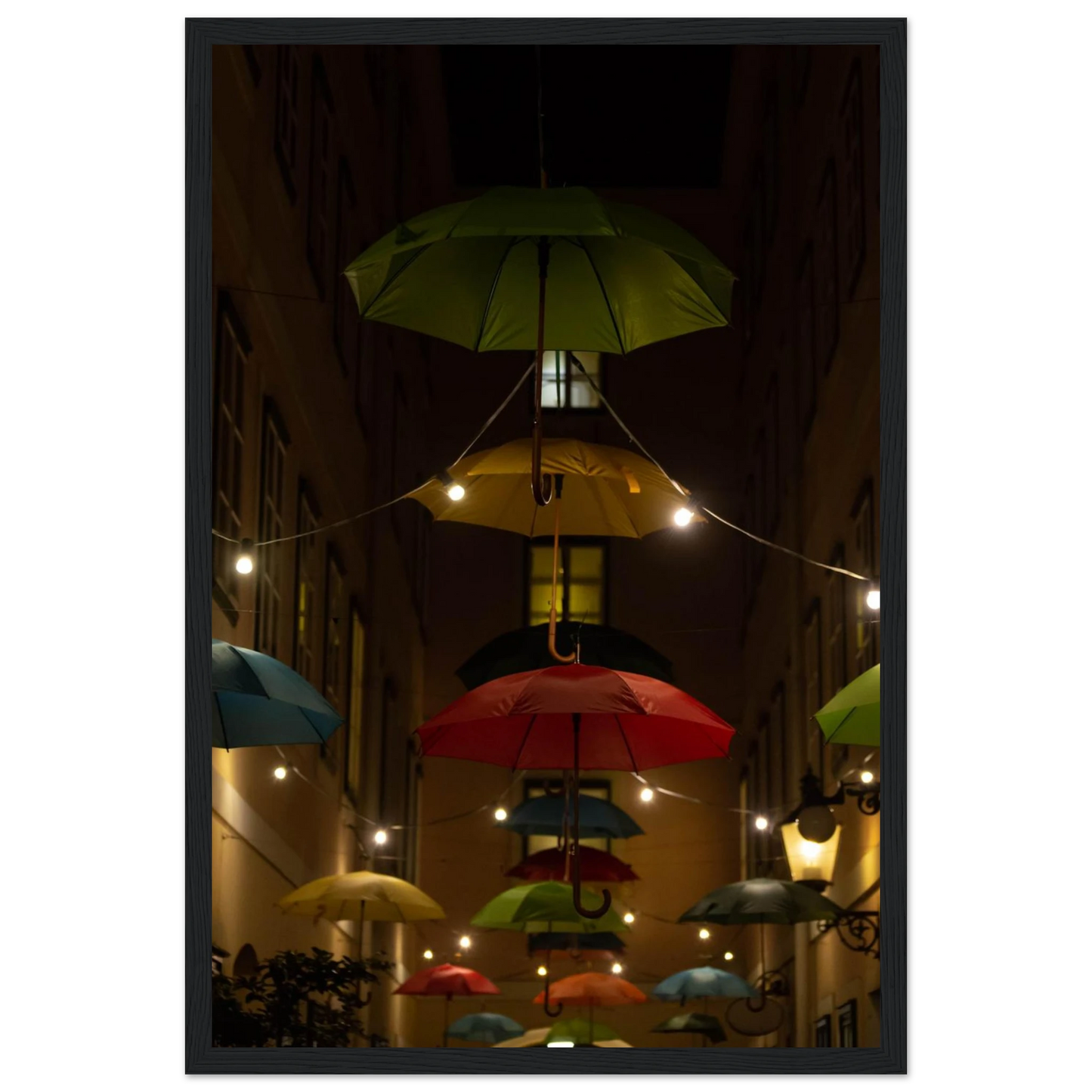 Nighttime street scene with colorful illuminated umbrellas hanging as decoration above a vibrant outdoor area on a wooden frame wall art