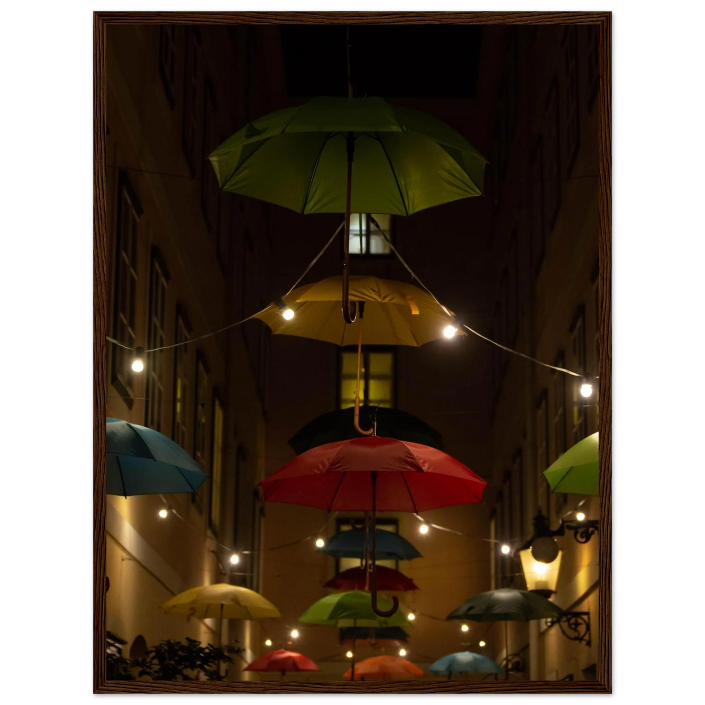 Nighttime street scene with colorful illuminated umbrellas hanging as decoration above a vibrant outdoor area on a wooden frame wall art