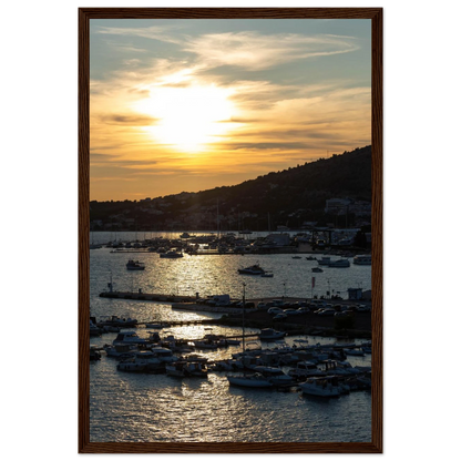 Wooden framed wall art of small boats anchored in a seaside port during Sunset at the harbor