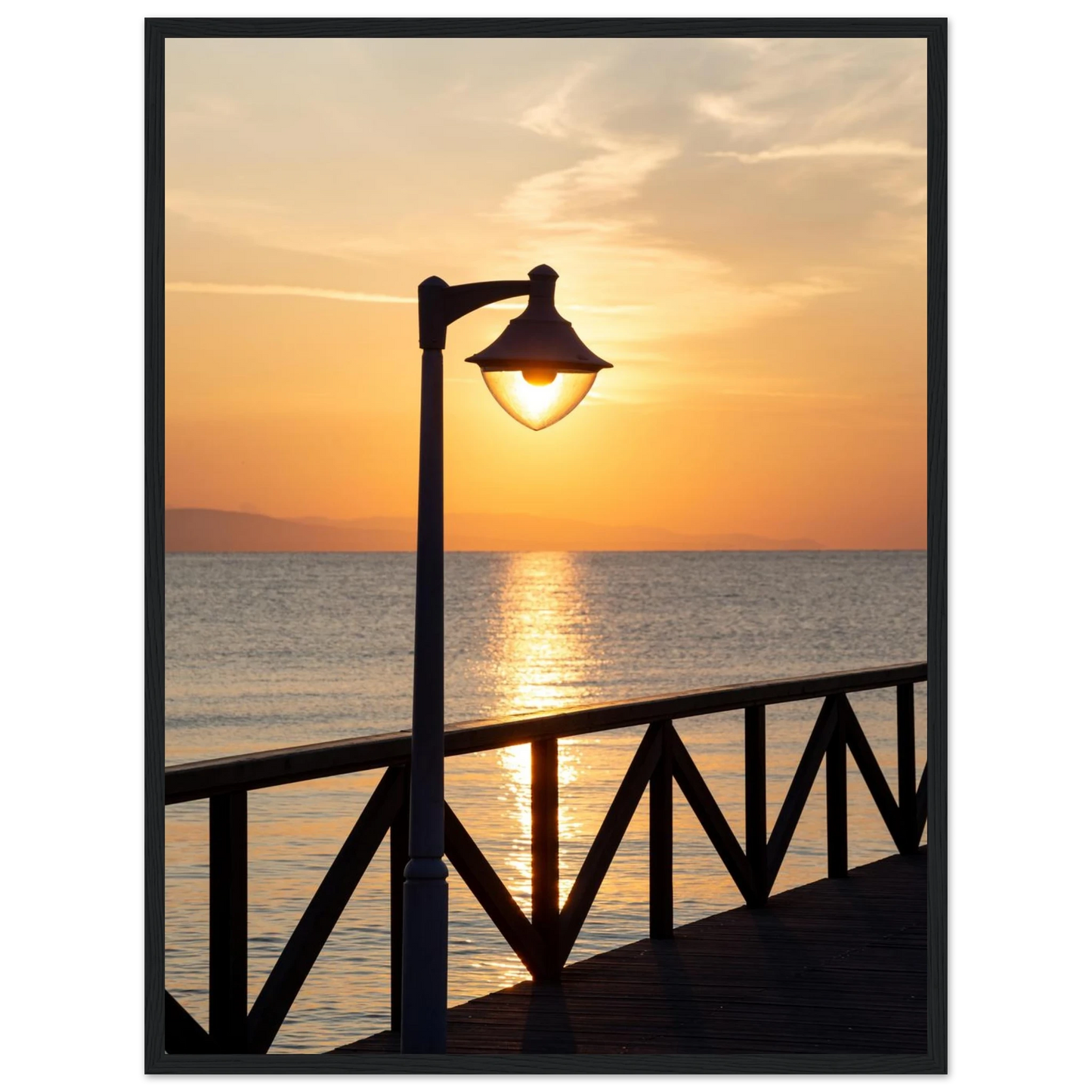 Wooden framed wall art of a sunset over the sea with a street lamp on the pier