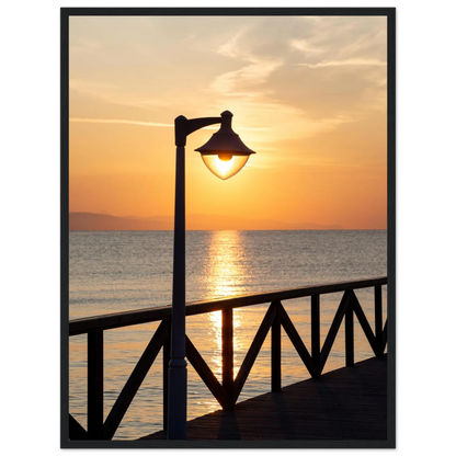 Wooden framed wall art of a sunset over the sea with a street lamp on the pier