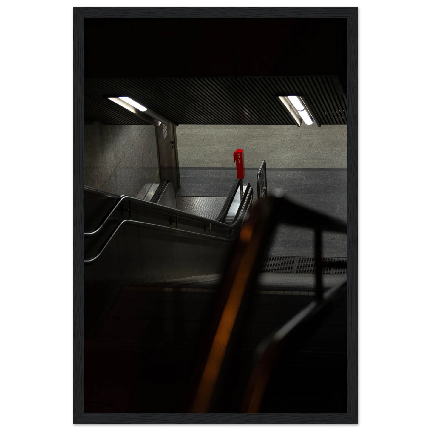 Nighttime view of a metro station entrance with illuminated signs and dark urban surroundings on wooden framed wall art
