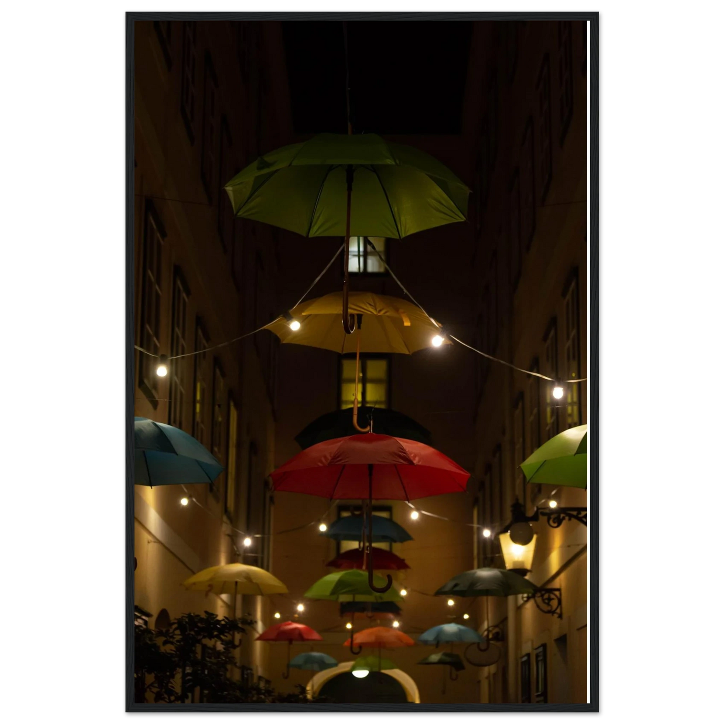 Nighttime street scene with colorful illuminated umbrellas hanging as decoration above a vibrant outdoor area on a wooden frame wall art