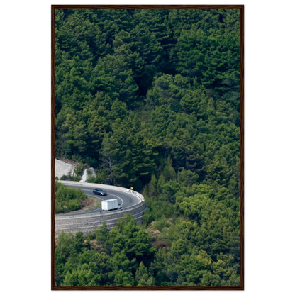 Aerial view of a winding road curve with cars surrounded by lush green forest landscape on wooden framed wall art