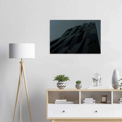 Black and white low angle view of a modern skyscraper with bold geometric lines and dark textured facade on Canvas Print wall art on the wall in the Livingroom
