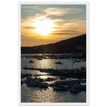 Wooden framed wall art of small boats anchored in a seaside port during Sunset at the harbor