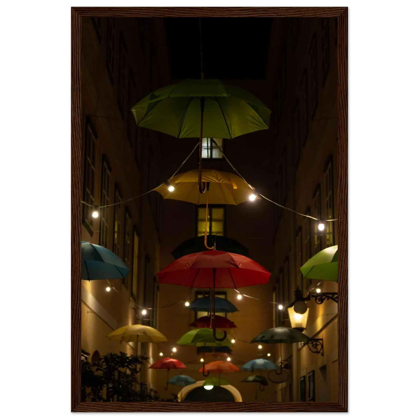 Nighttime street scene with colorful illuminated umbrellas hanging as decoration above a vibrant outdoor area on a wooden frame wall art