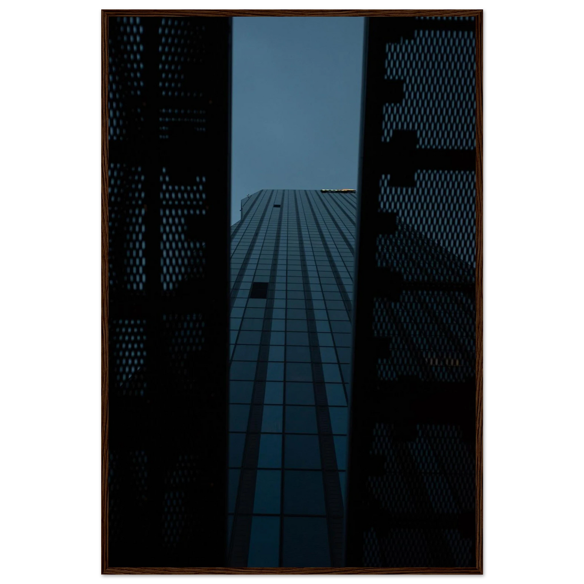 Low angle view looking up at a tall glass skyscraper framed between two metal structural elements on wooden framed wall art