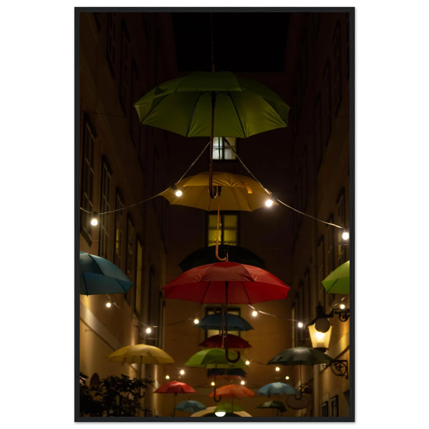 Nighttime street scene with colorful illuminated umbrellas hanging as decoration above a vibrant outdoor area on a wooden frame wall art