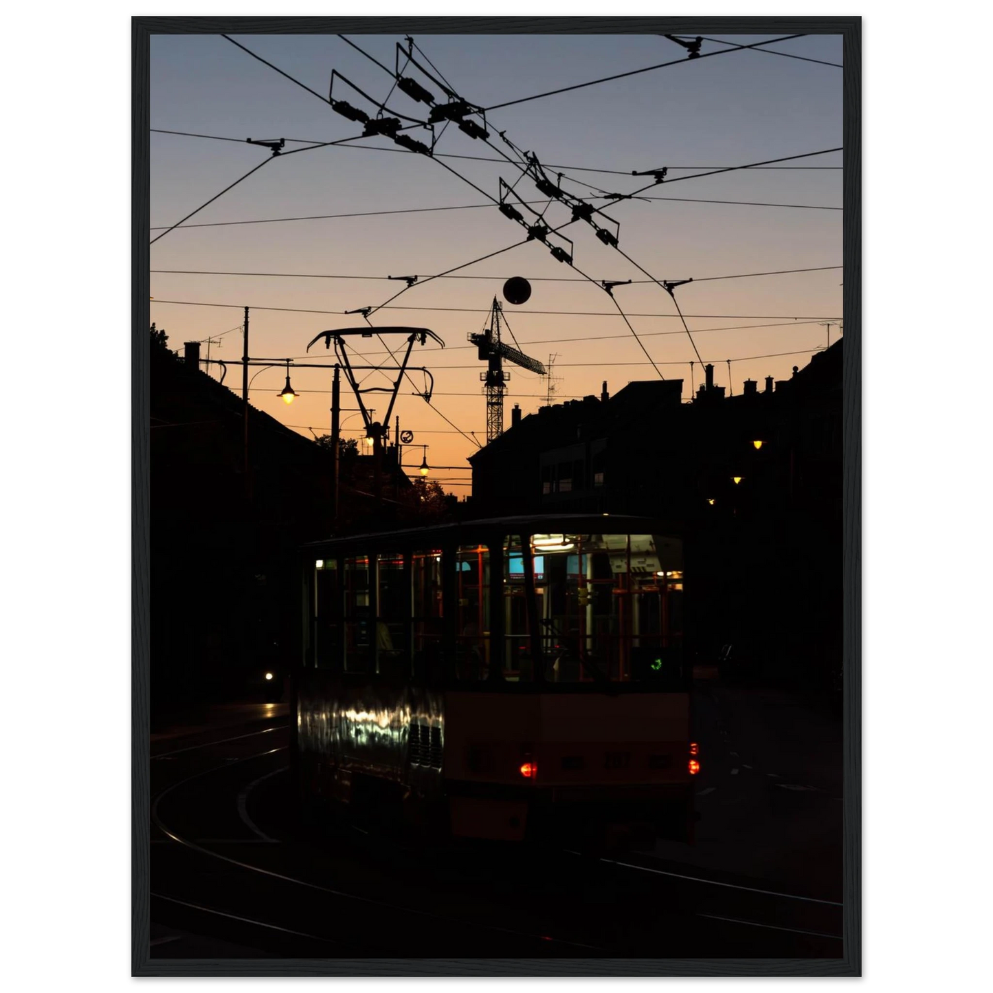Wooden framed wall art featuring a tram the Nightline driving between houses under power lines during a golden sunset