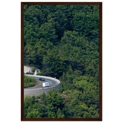Aerial view of a winding road curve with cars surrounded by lush green forest landscape on wooden framed wall art