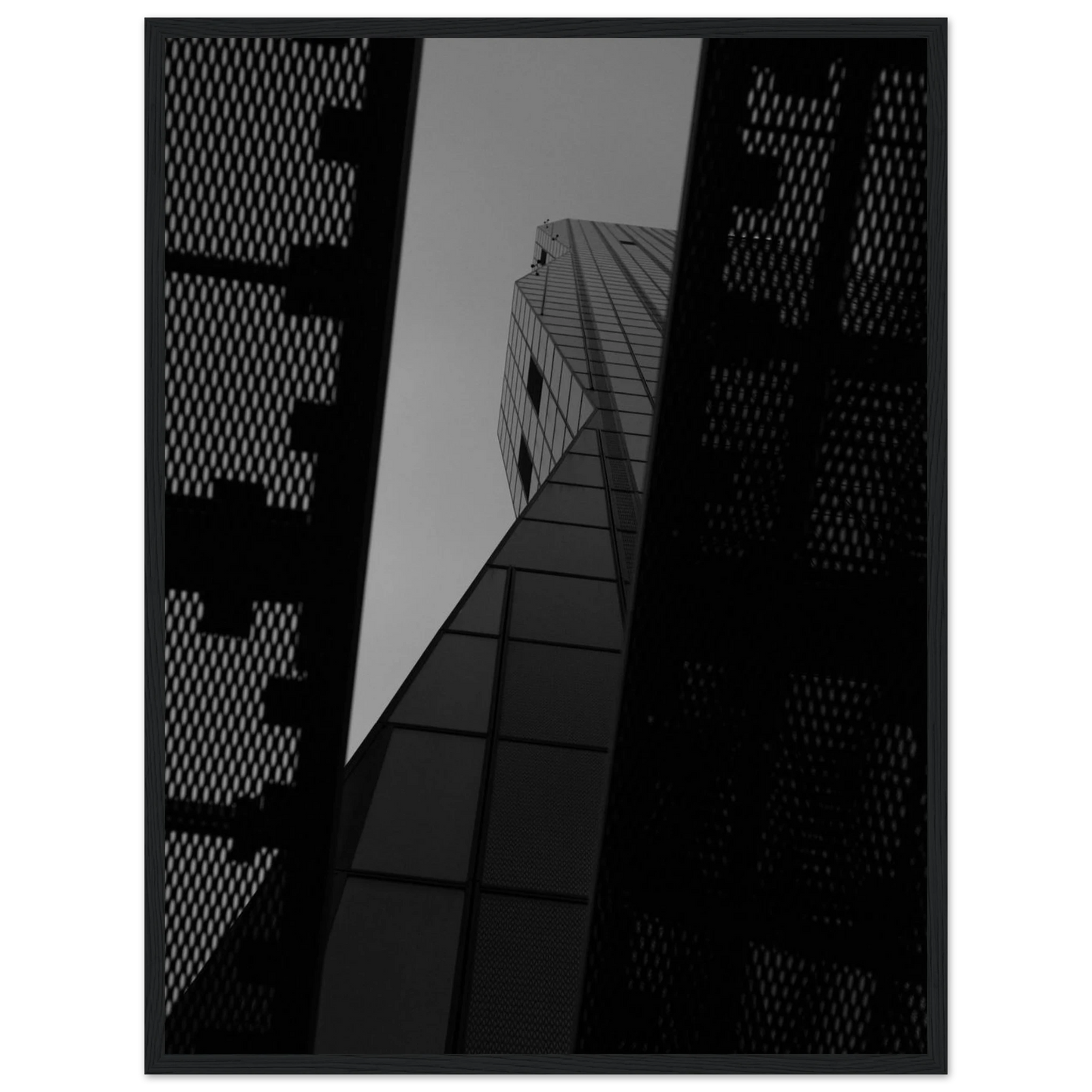 Black and white Low angle view looking up at a tall glass skyscraper framed between two metal structural elements on Wooden frame wall art