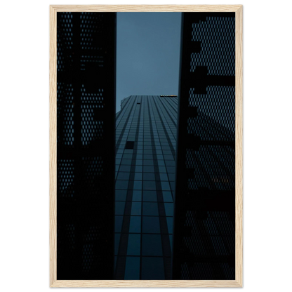 Low angle view looking up at a tall glass skyscraper framed between two metal structural elements on wooden framed wall art